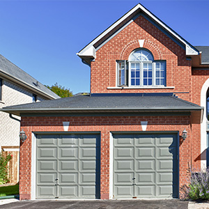 brick home with rounded entrance and gray garage door